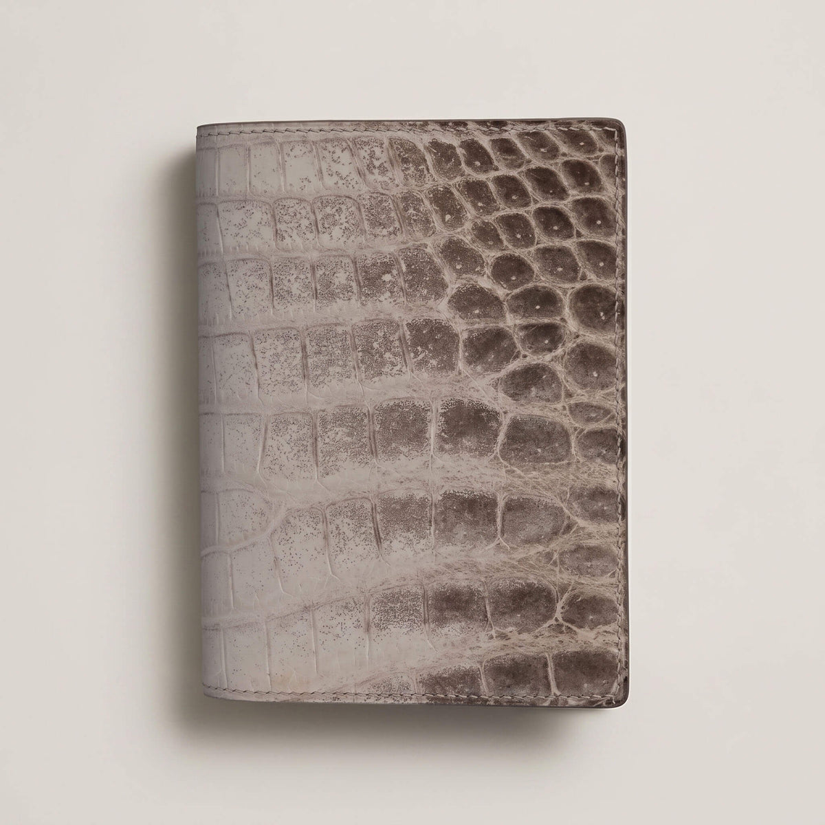 Front view of a closed bespoke passport cover showcasing the natural white-to-grey gradient of matte French Himalayan crocodile leather with hand-painted edges.