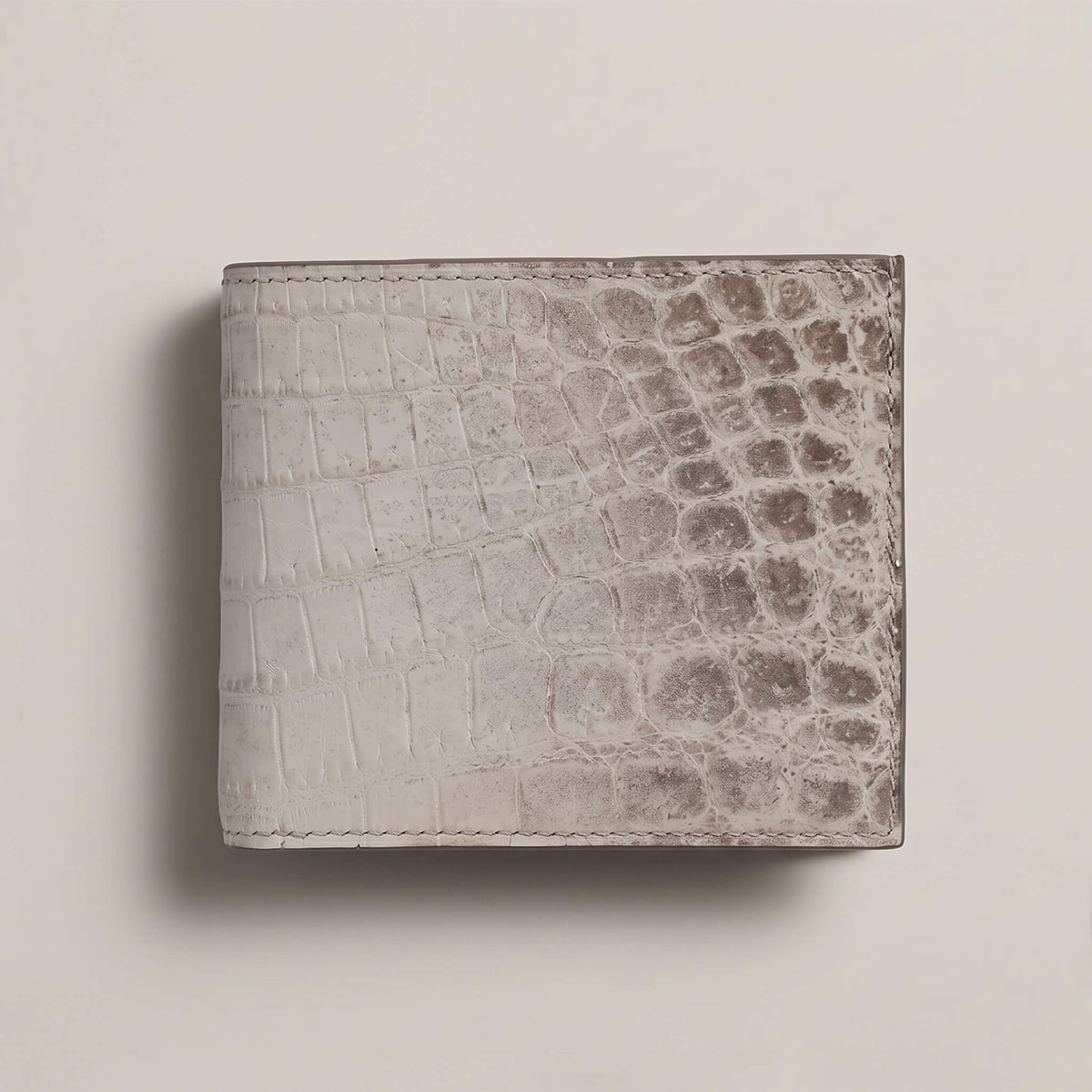 Front exterior view of a closed bifold wallet in matte French Himalayan crocodile leather, showing natural white-to-grey gradient scales and hand stitching.