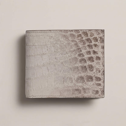 Front exterior view of a closed bifold wallet in matte French Himalayan crocodile leather, showing natural white-to-grey gradient scales and hand stitching.