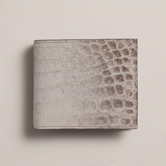 Front exterior view of a closed bifold wallet in matte French Himalayan crocodile leather, showing natural white-to-grey gradient scales and hand stitching.