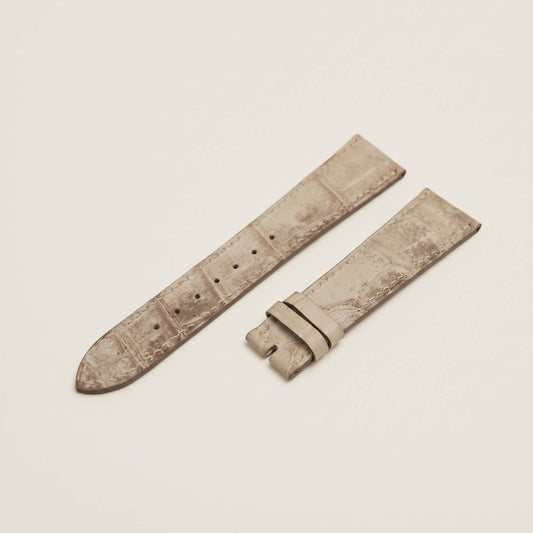 Front view of a bespoke Himalayan crocodile leather watch strap in matte bone-to-grey gradient with tapered padding on a soft grey background.