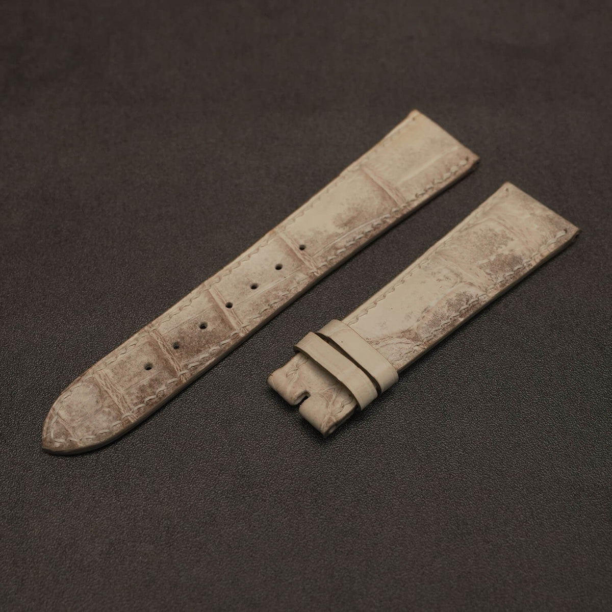 Macro close-up of matte Himalayan crocodile watch band highlighting organic scale texture, natural gradient, and off-white French linen stitching.