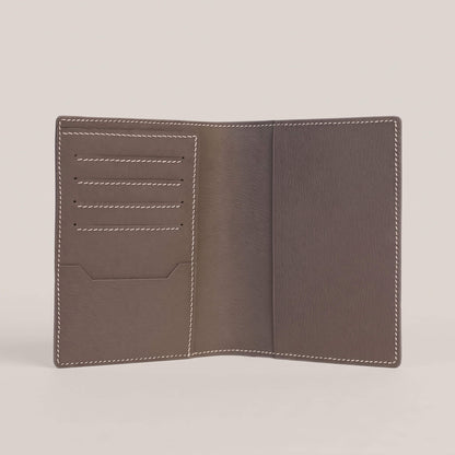 Fully opened interior of the passport wallet lined in Étoupe French Alran goatskin, featuring four card slots, an itinerary slip pocket, and contrasting white hand stitching.