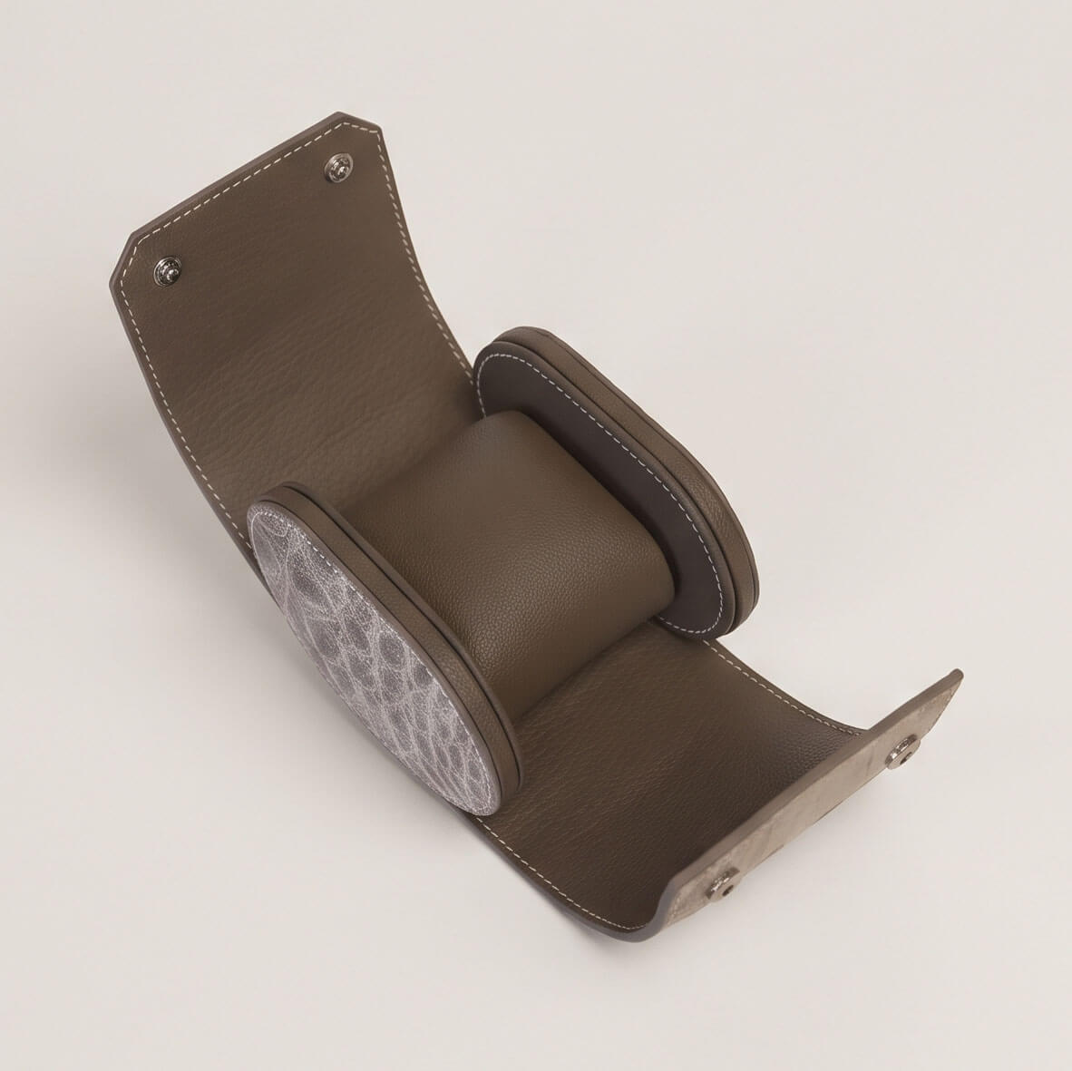 Interior of the open single watch case with an empty Étoupe goatskin cushion secured inside protective side walls.